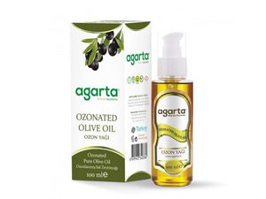 Bottles of natural oils including black seed, olive, and argan placed on a rustic surface with fresh herbs and ingredients.