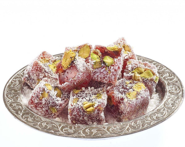 Assorted Turkish Delight cubes in rose, pistachio, and fruit flavors dusted with powdered sugar, served on a traditional plate.