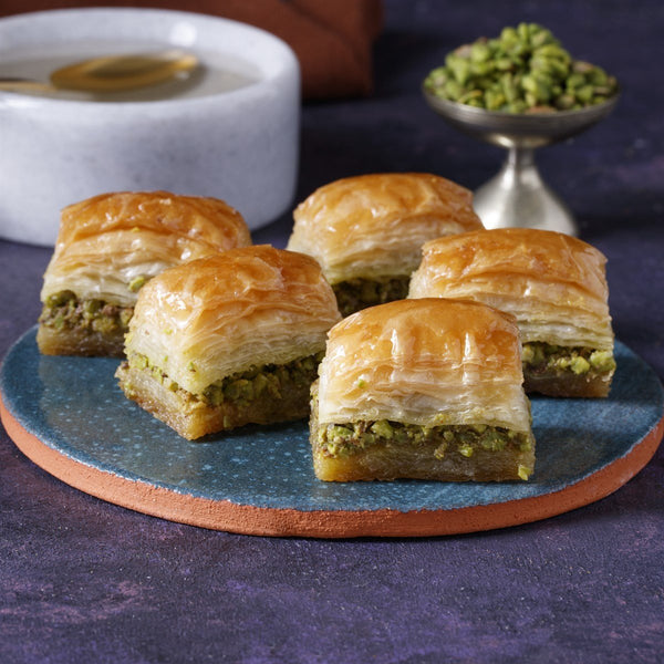 Freshly made Turkish baklava layered with pistachios and soaked in honey syrup, displayed on a traditional serving plate.